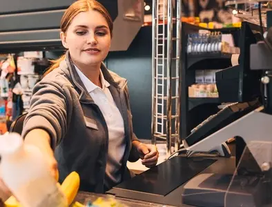Young woman cashier working at counter  Female employee in a grocery store working at checkout