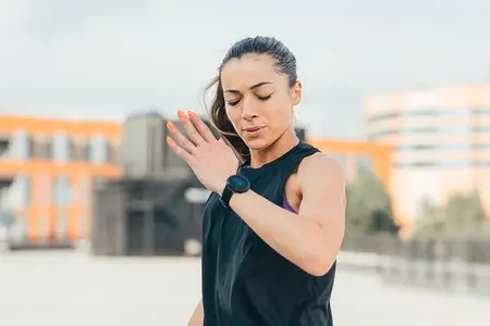 Woman in sportswear is warming up before an outdoor workout  running in one place with closed eyes