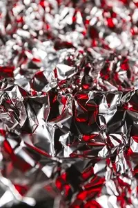 Shiny crumpled foil with silver and red reflections creating a metallic abstract design  Futuristic texture with chrome surface and cyberpunk background style