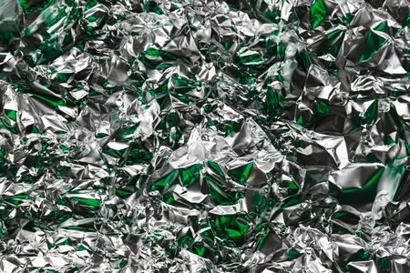 Crumpled foil with silver and green reflections  metallic abstract style  futuristic texture  chrome surface and cyberpunk pattern