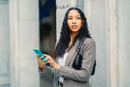 A Stylish Young Woman Engaging with Her Smartphone While in an Urban City Setting