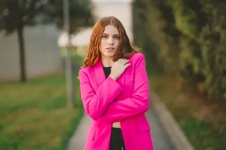 A Chic Young Woman is Posing Outdoors in a Bright Pink Blazer  Radiating Confidence and Style