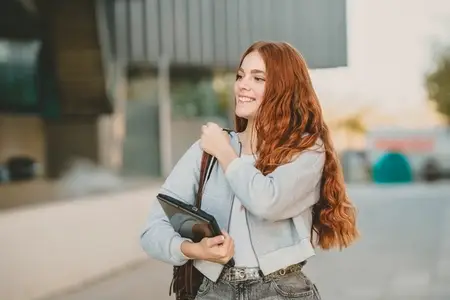 A Young Woman with Vibrant Red Hair is Joyfully Smiling in a Bustling Urban Setting