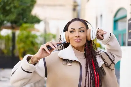 A Joyful Woman Enjoying Her Favorite Music While Outdoors Wearing Headphones in Daylight