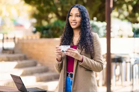 A young woman enjoys coffee and works on her laptop outside  embracing inspiration