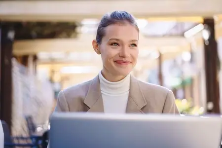 A Professional Businesswoman Diligently Working on Her Laptop in a Modern Outdoor Setting