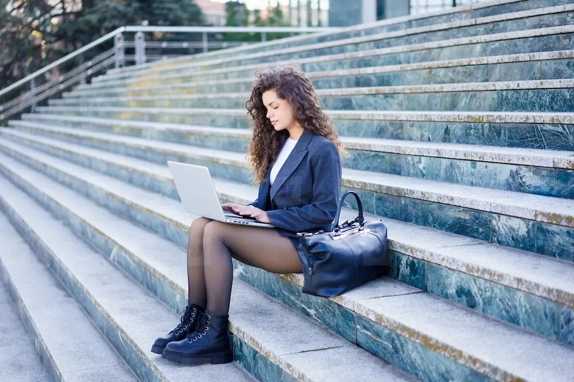 A Young Woman Works Intently On Her Laptop Outdoors, Displaying Focus ...