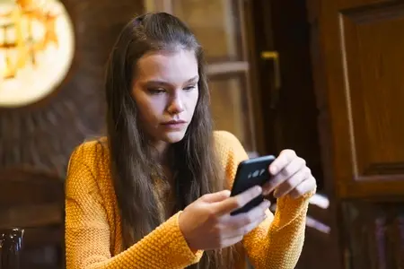 A young woman is using her smartphone while sitting in a cozy cafe  enjoying her time