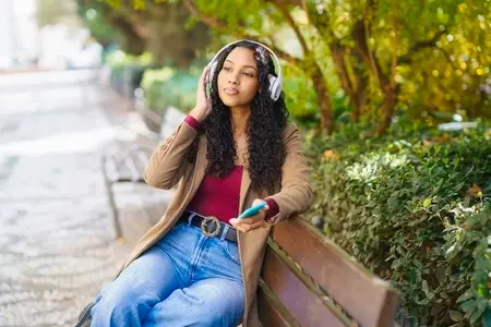 A Young Woman is Enjoying Music in a Relaxing Park Setting Filled with Beautiful Nature
