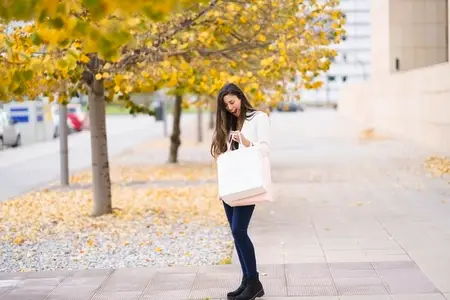An Autumn Stroll A Graceful Woman Dressed in a Chic White Blazer Carrying a Shopping Bag