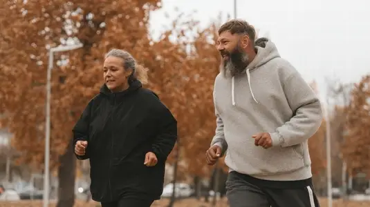 Overweight couple jogging together autumn park  happy middle aged man and woman exercise outdoors