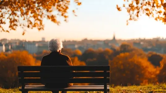 Senior woman sitting on park bench autumn cityscape peaceful thoughtful golden hour