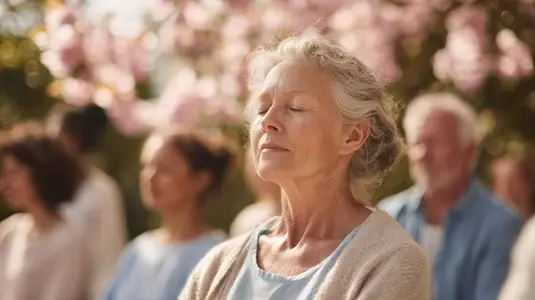 Senior woman meditating outdoors  peaceful expression  group session  spring  soft sunlight