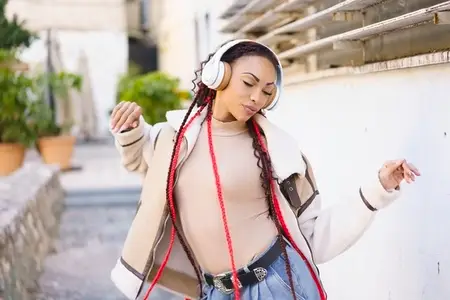 A Young Woman has a wonderful experience Enjoying Music Outdoors while wearing Headphones
