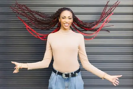 A Vibrant Woman with Beautifully Braided Hair Posing Gracefully Against a Stylish Background