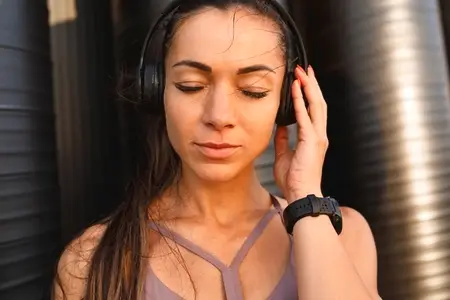 High detailed close up portrait of a young sportswoman with long hair enjoying music with closed eyes