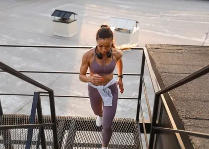 Full length of a muscular female runner on the stairs on the roof  Woman in fitness attire running on the roof stairs