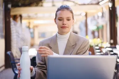 A Young Professional Actively Engaged in Work with Their Laptop and a Water Bottle Nearby