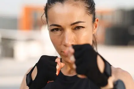 Close up high detailed portrait of a young sportswoman standing in a battle pose and looking at camera