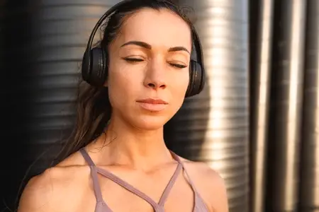 Close up high detailed portrait of a young woman during a workout break  Fitness female with closed eyes and clean skin enjoying music