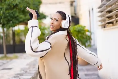 A Joyful Woman Wearing Headphones Dancing Happily in an Outdoor Urban Environment
