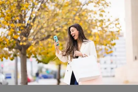 A Joyful Young Woman Enjoys Shopping in a Beautiful Autumn Park Filled with Colorful Leaves