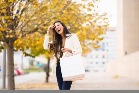 A Joyful Young Woman Enjoying a Day of Shopping in a Beautiful Autumn Park Setting