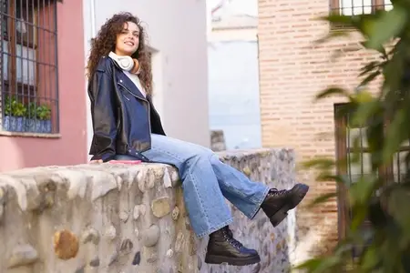 A Young Woman is Enjoying her Relaxation on a Stone Wall Within an Urban Cityscape