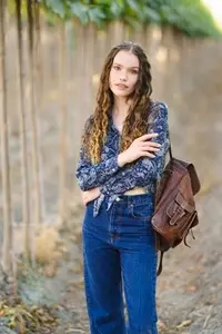 A Stylish Young Woman Wearing Denim and a Floral Top Posing Confidently in a Natural Setting