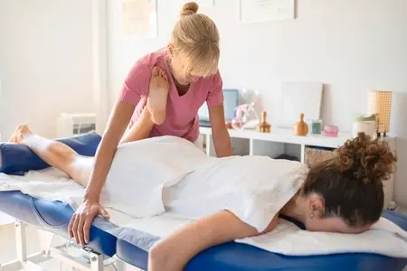Serious masseuse doing massage on leg of female client