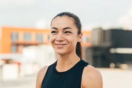Portrait of a young cheerful female athlete standing on the roof
