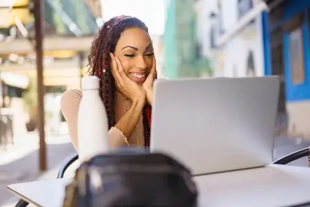 Smiling Woman Using Laptop at Outdoor Caf