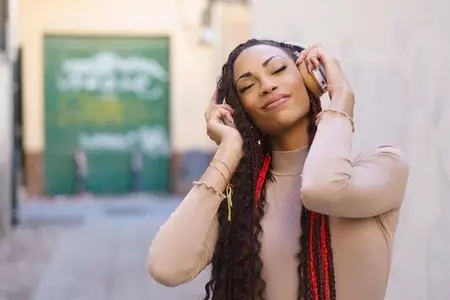 A joyful woman is fully enjoying her music amidst a lively urban setting filled with energy