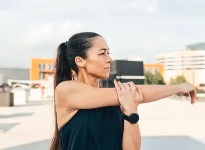 Young slim sportswoman stretching her hand before a workout on the roof