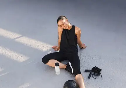 Young slim female relaxing on the roof after intense workout  Tired woman in black fitness attire relaxing with closed eyes
