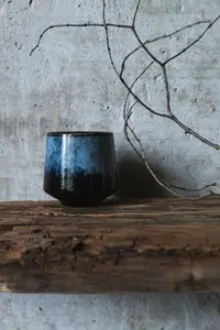 Dark ceramic cup on rustic wood with dry branch against concrete wall  minimal wabi sabi still life with natural textures