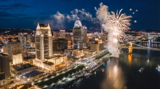 Aerial cityscape night view with fireworks  river  illuminated buildings  festive atmosphere