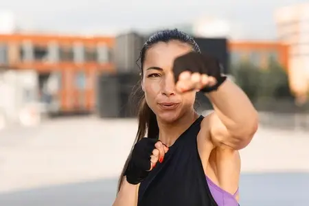 Young female practicing punches outdoors  wearing gloves  Portrait of a young woman during an intense warm up