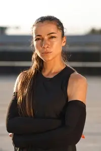 Portrait of a young sportswoman with arms crossed  Highly detailed portrait of a female runner wearing arm sleeves looking at camera