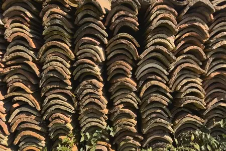 Curved roof tiles stacked in rows in sunlight