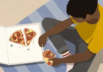View from above teenage boy eating pizza from box on floor