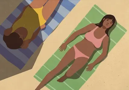 Young women sunbathing on towels on sunny summer beach