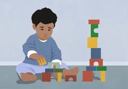 Toddler boy playing stacking toy blocks on floor