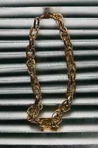 Golden chain necklace on metallic fabric background  luxury accessory with elegant texture and stylish modern composition