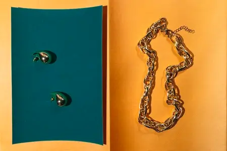 Golden chain and abstract earrings on colorful paper background  modern jewelry composition with geometric light and contrast