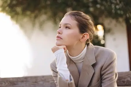 A Thoughtful Young Woman Dressed in Stylish Attire Deep in Contemplation While Outdoors