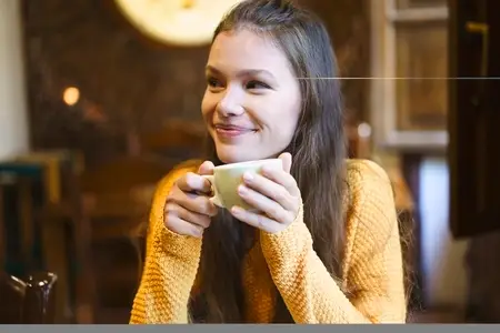 Cheerful and Happy Young Woman Enjoying a Warm Beverage While Relaxing in a Cozy Cafe setting