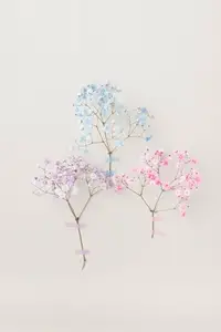 Delicate pastel flowers from floral series in blue  pink  and lilac taped to a light wall  minimal floral composition