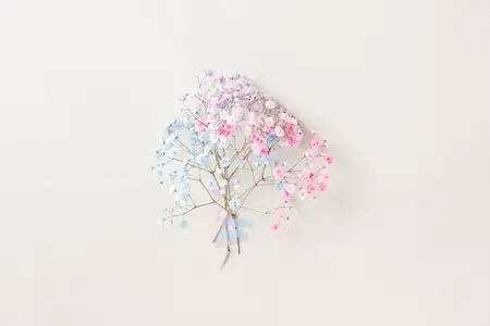 Delicate pastel flowers from floral series in blue  pink  and lilac taped to a light wall  minimal floral composition