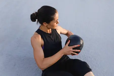 High angle of a slim sportswoman exercising with medicine ball outdoors  Muscular female athlete practicing core workout